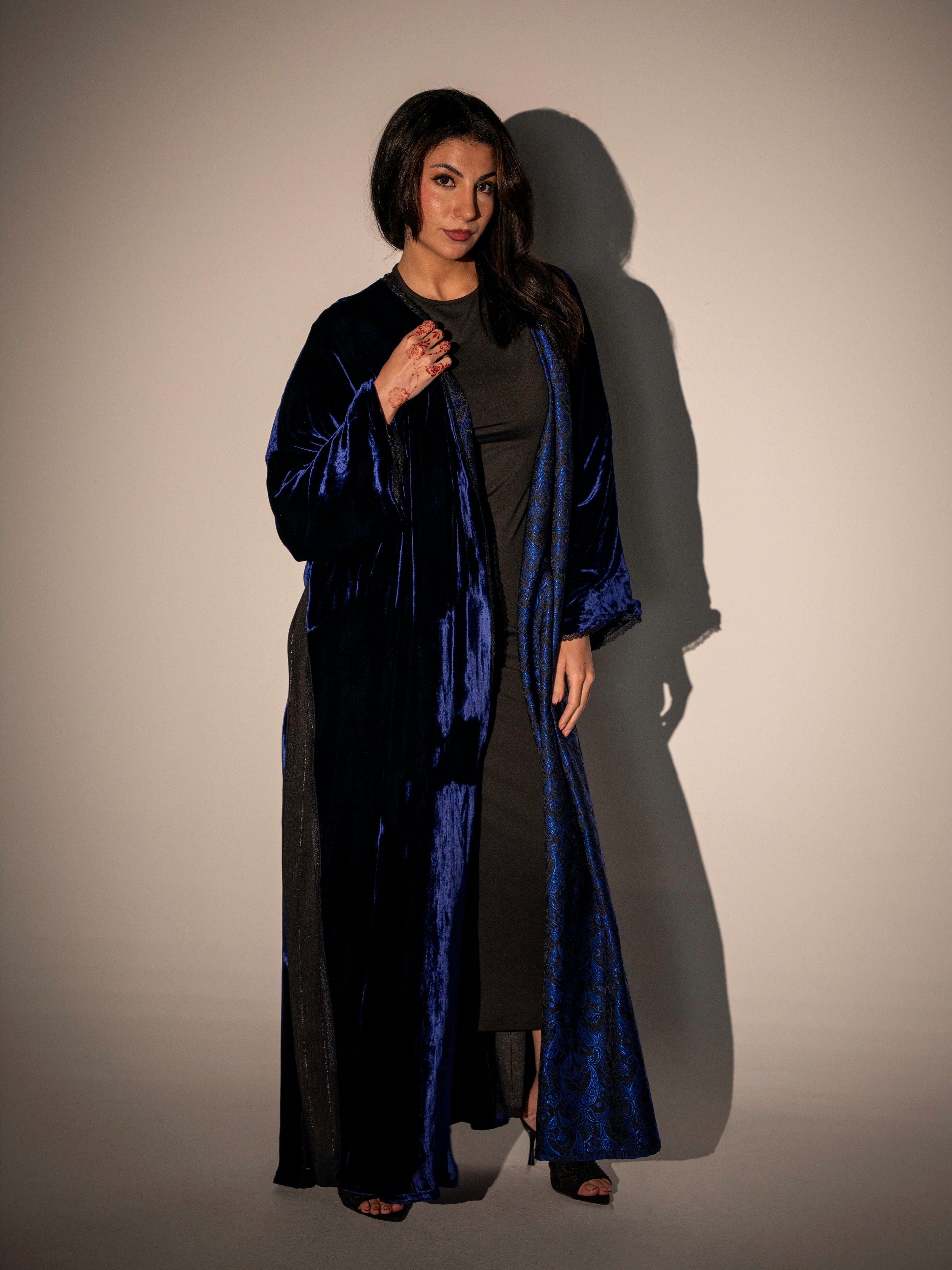 Woman wearing a long, dark blue robe against a neutral background