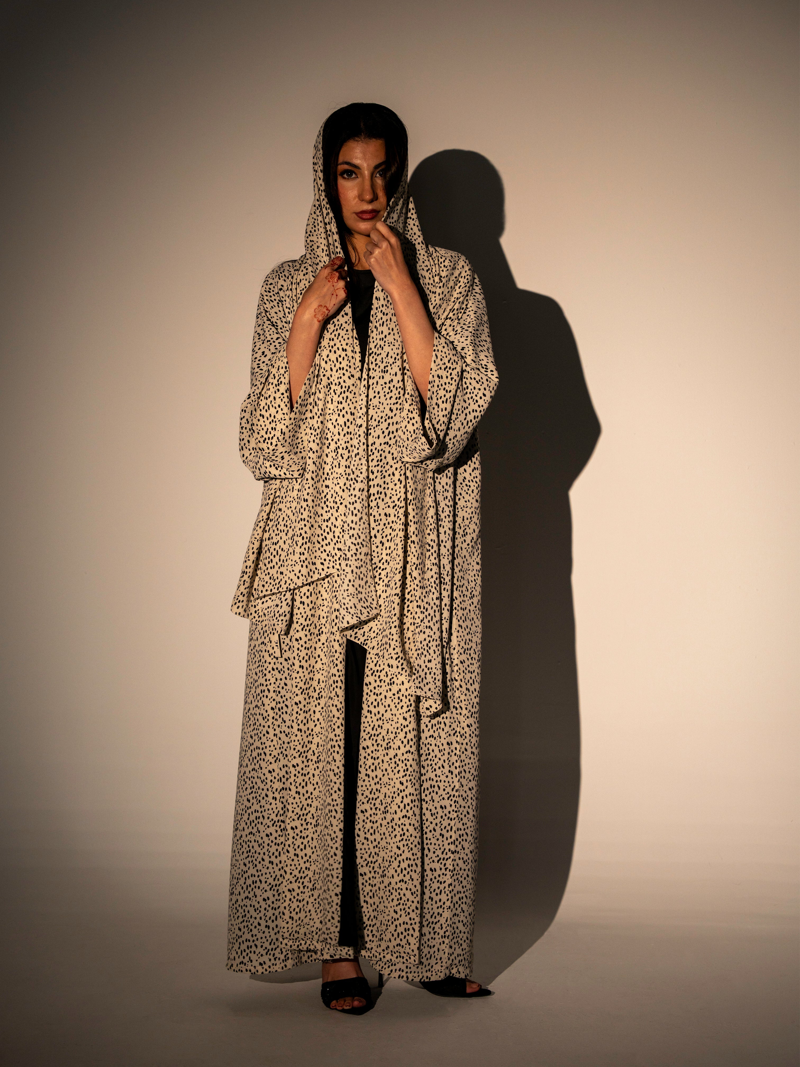 Person wearing a long, patterned coat against a neutral background